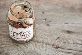 A glass jar with coins in labelled Donate.