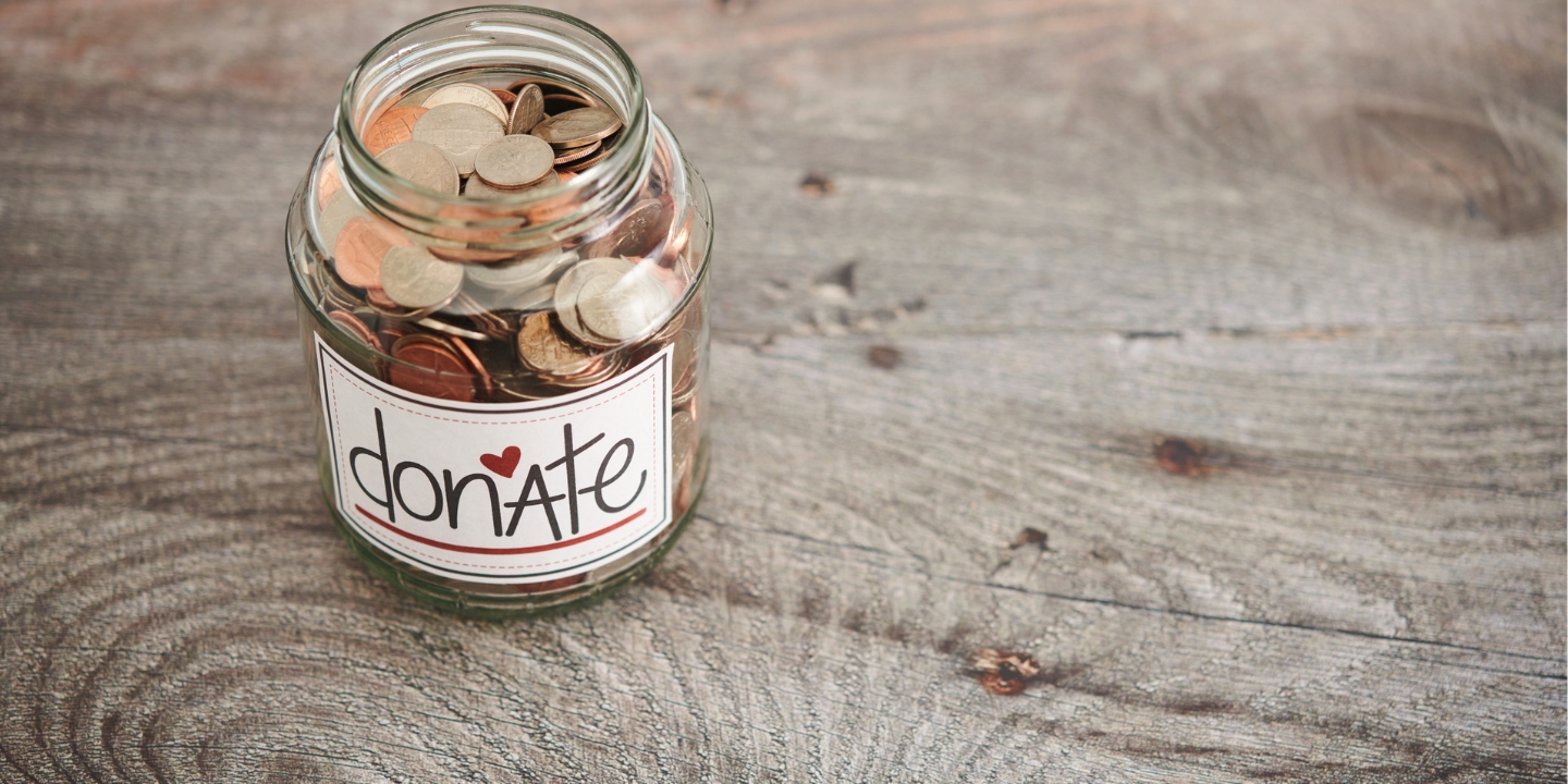 A glass jar with coins in labelled Donate.