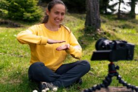 photo of a lady sitting the forest filming herself