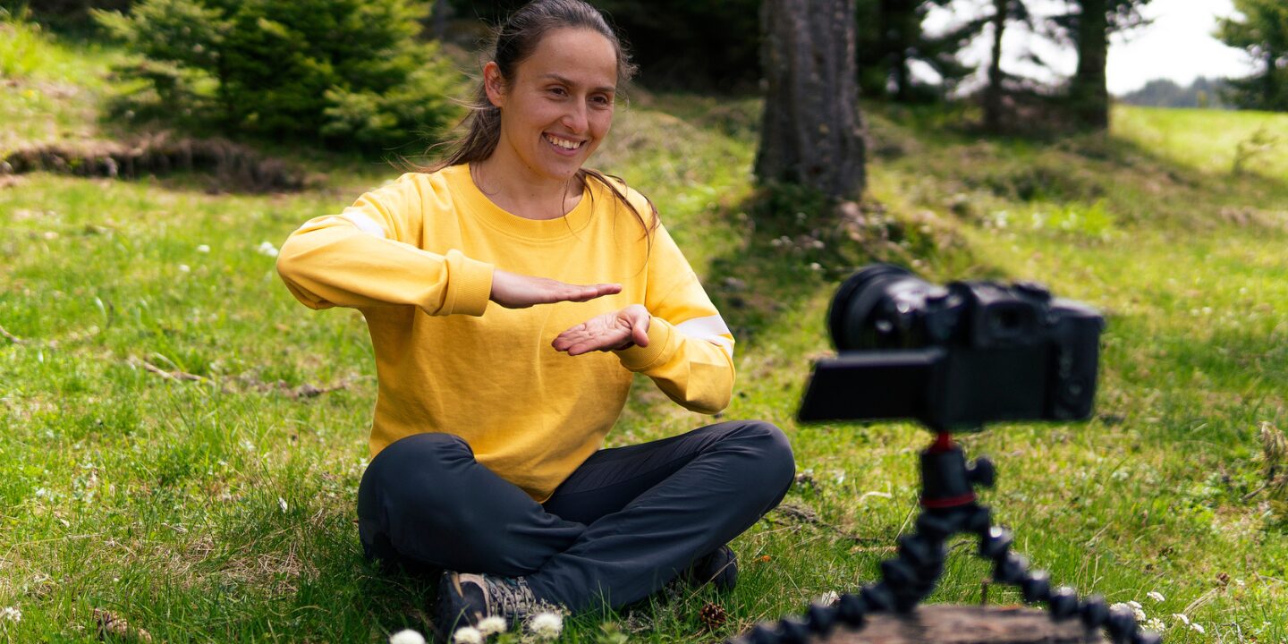 photo of a lady sitting the forest filming herself